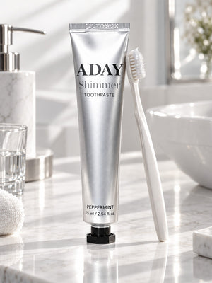 ADAY Silver Shimmer Toothpaste standing on a marble vanity beside a toothbrush