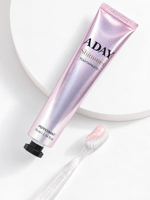 ADAY Pink Shimmer Toothpaste on a white pedestal beside a toothbrush and a swirl of paste