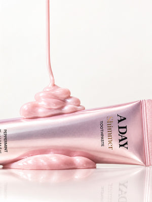 Pink shimmer paste pouring over the ADAY Pink Shimmer Toothpaste tube