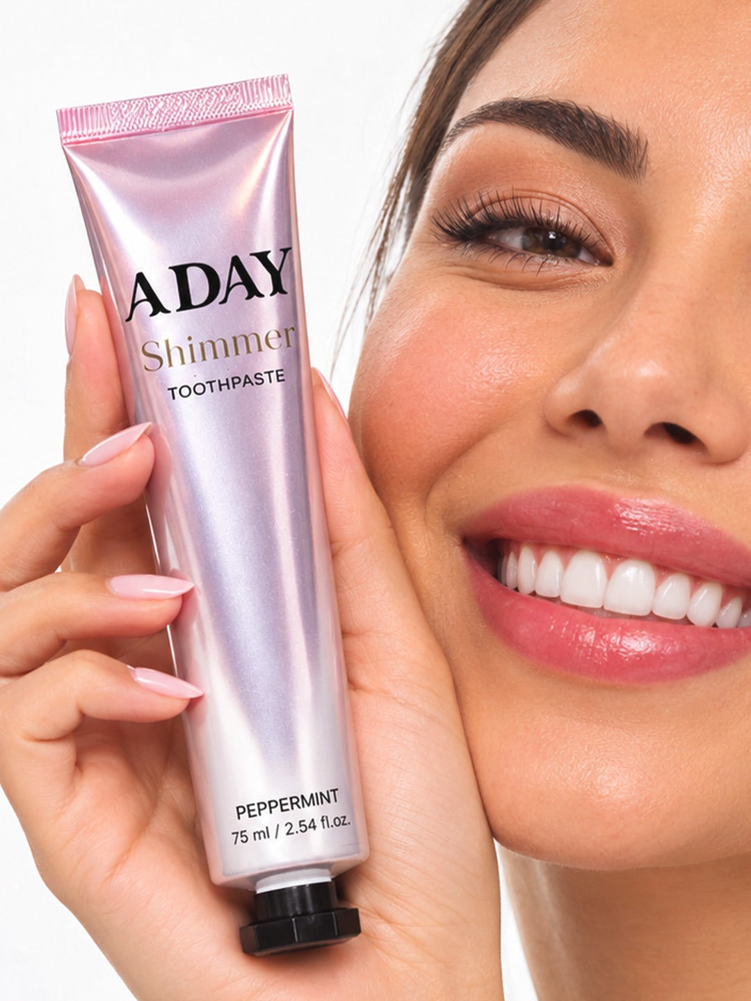 A model holding the ADAY Pink Shimmer Toothpaste beside her smile